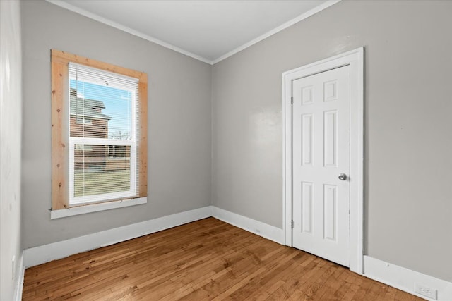 spare room with ornamental molding, baseboards, and hardwood / wood-style flooring