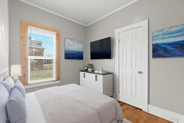 bedroom featuring light wood finished floors and crown molding