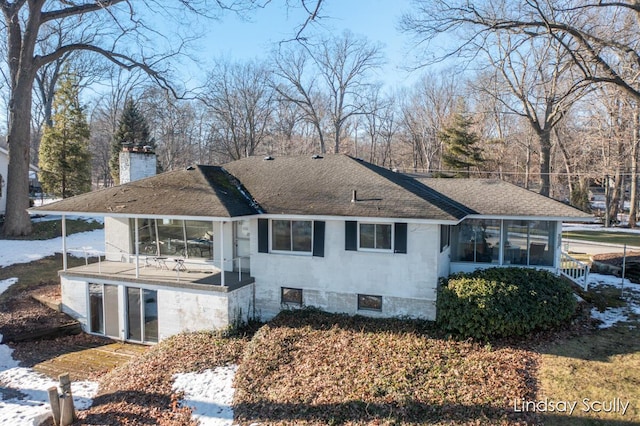 exterior space with a shingled roof, a sunroom, and a chimney