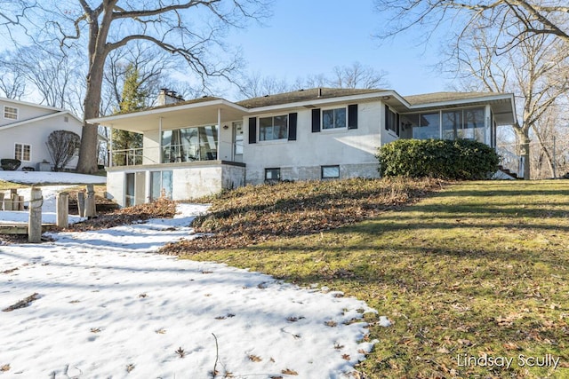 view of front of house with a yard, a chimney, a sunroom, a carport, and driveway