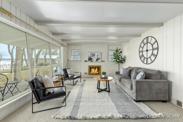 living area featuring visible vents, a lit fireplace, carpet, and beam ceiling