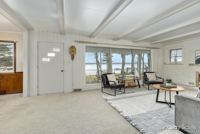 interior space with visible vents, plenty of natural light, beam ceiling, and wooden walls