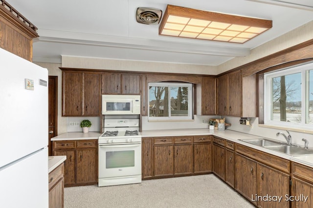 kitchen with light countertops, visible vents, ornamental molding, a sink, and white appliances