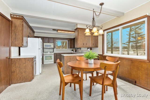 dining area featuring ornamental molding, beamed ceiling, wood walls, and an inviting chandelier