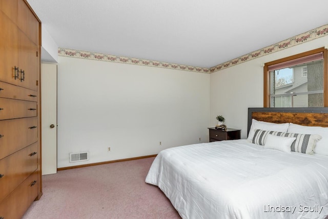 bedroom with baseboards, visible vents, and light colored carpet