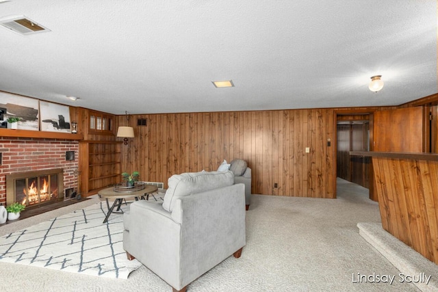 carpeted living room with wooden walls, visible vents, a fireplace, and a textured ceiling