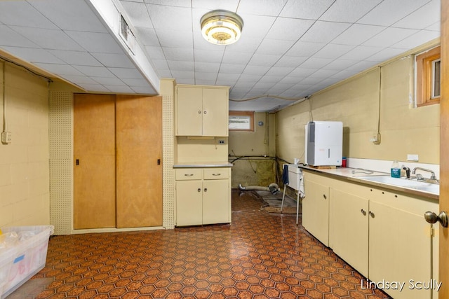 kitchen with light countertops, dark floors, cream cabinets, and a sink