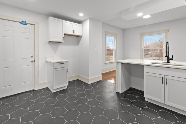 clothes washing area featuring baseboards, dark tile patterned floors, a sink, and recessed lighting