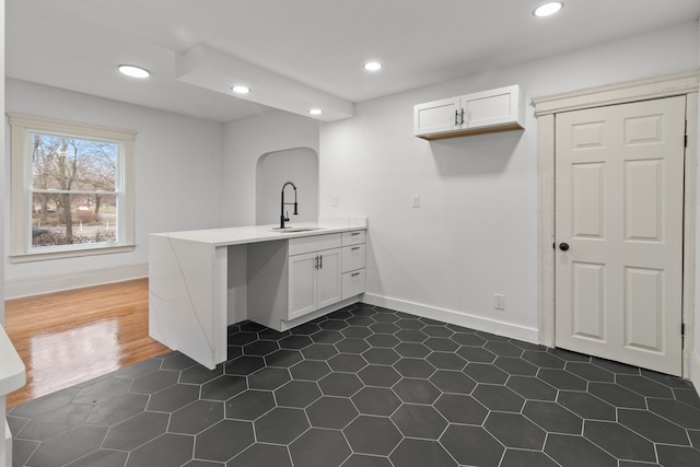 interior space with a peninsula, white cabinets, a sink, and recessed lighting