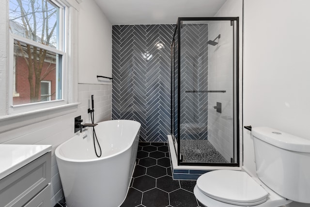 bathroom with toilet, a freestanding tub, a shower stall, and tile walls