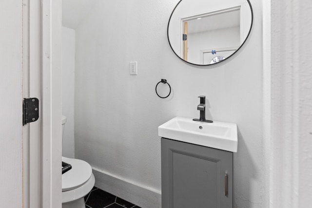 half bath with toilet, baseboards, vanity, and tile patterned floors