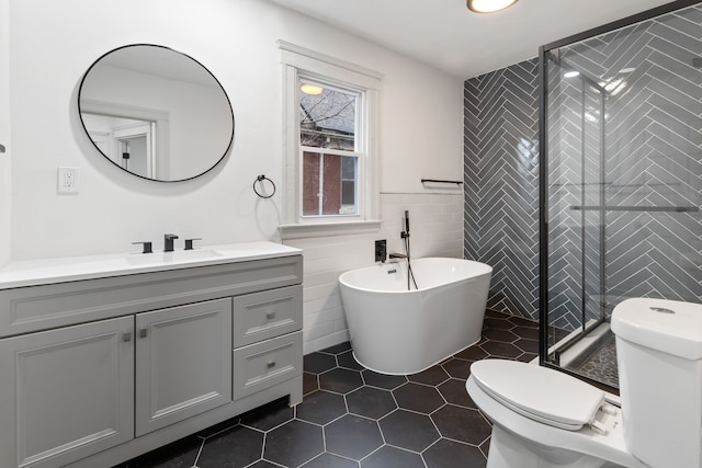 bathroom featuring tile walls, toilet, a shower stall, vanity, and tile patterned flooring