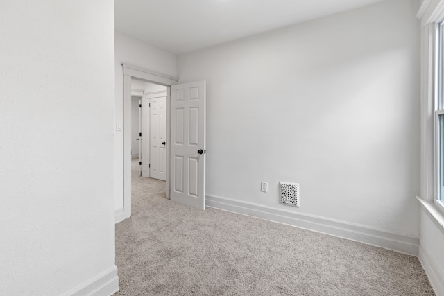 empty room with baseboards, visible vents, and carpet flooring