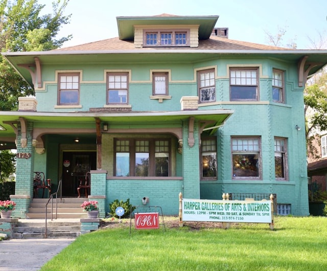 view of front facade with covered porch, brick siding, and a front lawn