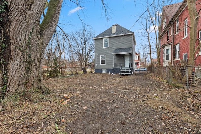 rear view of property featuring a shingled roof and fence