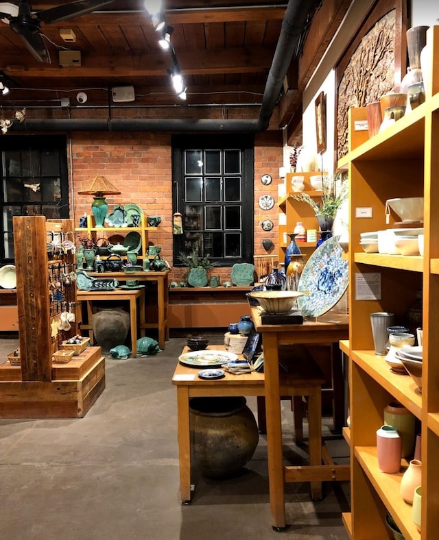 misc room featuring concrete flooring, brick wall, and a workshop area