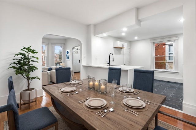 dining area featuring arched walkways, wood finished floors, a wealth of natural light, and baseboards