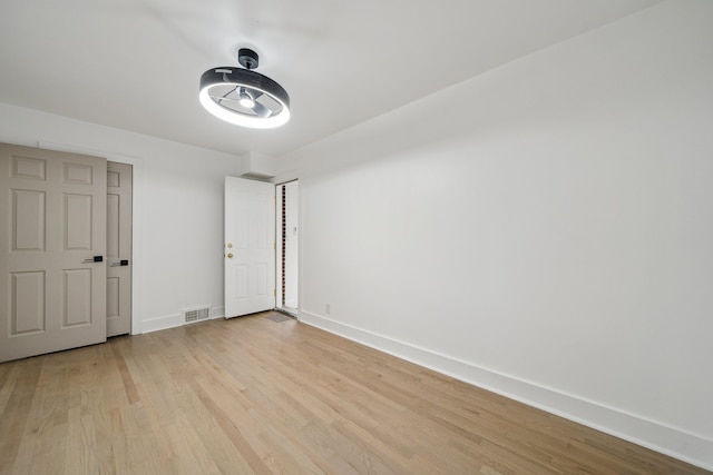 empty room featuring light wood-style floors, baseboards, and visible vents