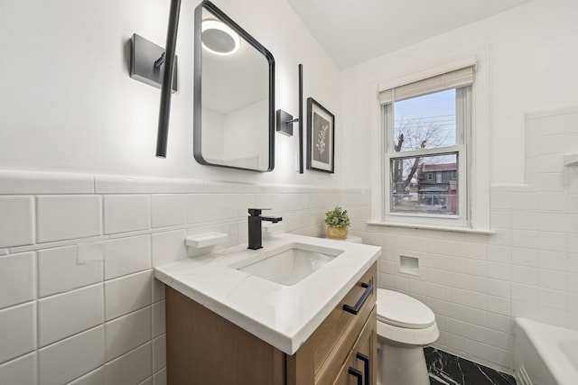 bathroom featuring a bathtub, vanity, toilet, and tile walls