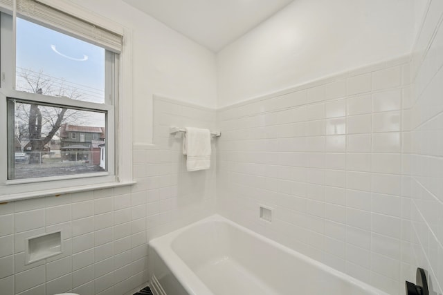 bathroom with a bathtub and tile walls