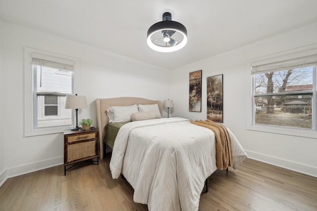 bedroom featuring multiple windows, wood finished floors, and baseboards