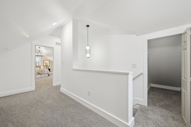 hallway featuring carpet floors, lofted ceiling, baseboards, and an upstairs landing