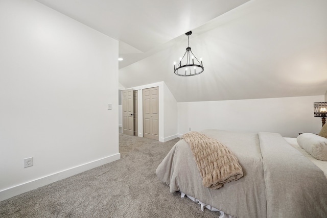 carpeted bedroom with a chandelier, a closet, vaulted ceiling, and baseboards