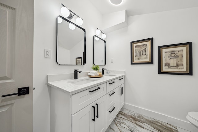 bathroom with marble finish floor, a sink, baseboards, and double vanity