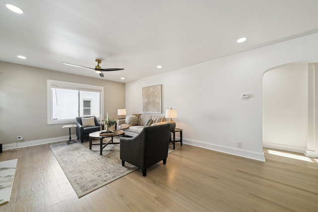 living area featuring arched walkways, recessed lighting, and wood finished floors