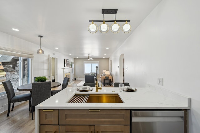 kitchen featuring open floor plan, light stone counters, arched walkways, and recessed lighting