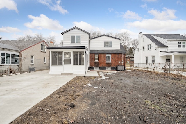 back of house with central AC, brick siding, fence, and a sunroom