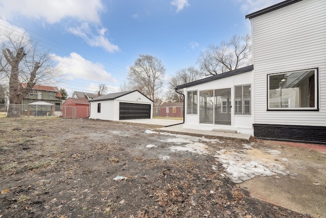 view of yard featuring an outbuilding, fence, a sunroom, and a garage