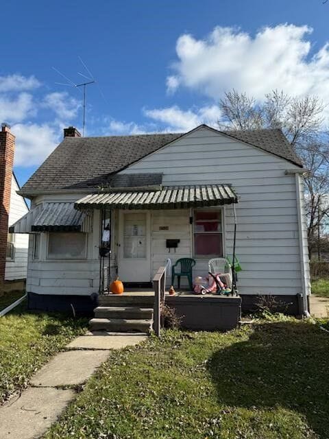 rear view of house featuring covered porch, roof with shingles, and a chimney