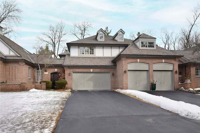 view of front of home with a garage, driveway, brick siding, and roof with shingles