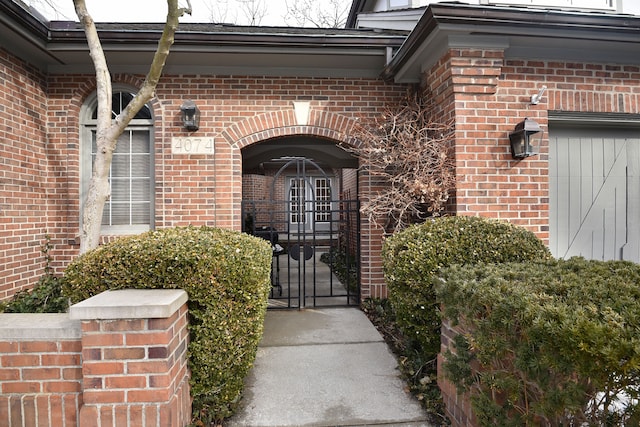 doorway to property featuring a gate and brick siding