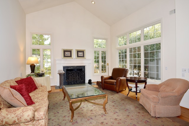 living room featuring visible vents, a fireplace, high vaulted ceiling, and wood finished floors