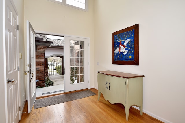 foyer featuring light wood finished floors, a high ceiling, and baseboards