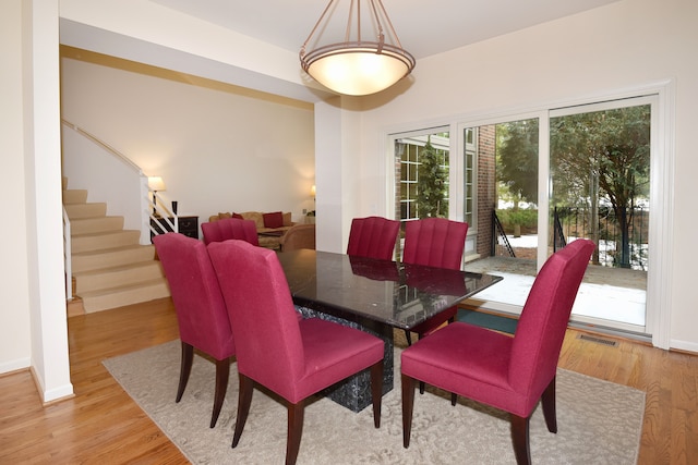 dining area featuring stairs, light wood finished floors, visible vents, and baseboards