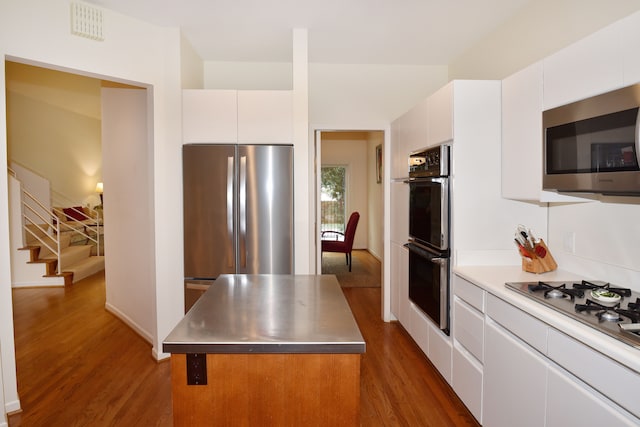 kitchen featuring dark wood-style flooring, stainless steel appliances, stainless steel countertops, visible vents, and white cabinets