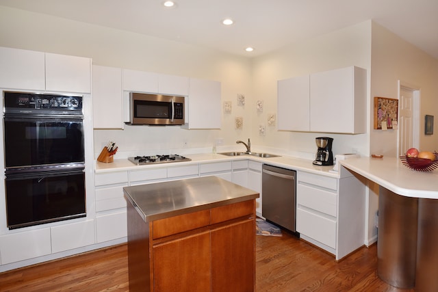 kitchen featuring stainless steel appliances, wood finished floors, a sink, and white cabinets