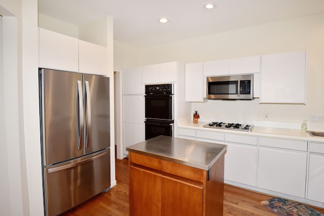 kitchen featuring recessed lighting, appliances with stainless steel finishes, light wood-style floors, white cabinets, and a kitchen island