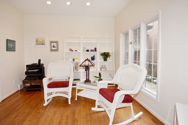 sitting room with baseboards, wood finished floors, and recessed lighting