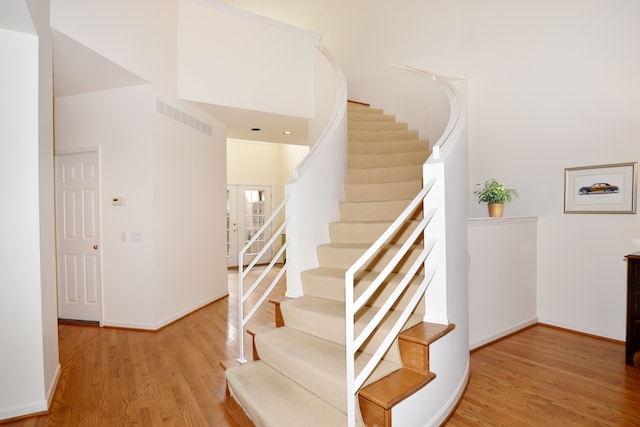 stairway featuring baseboards, visible vents, and wood finished floors