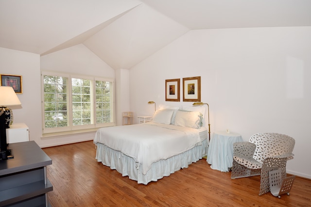 bedroom with vaulted ceiling and wood finished floors