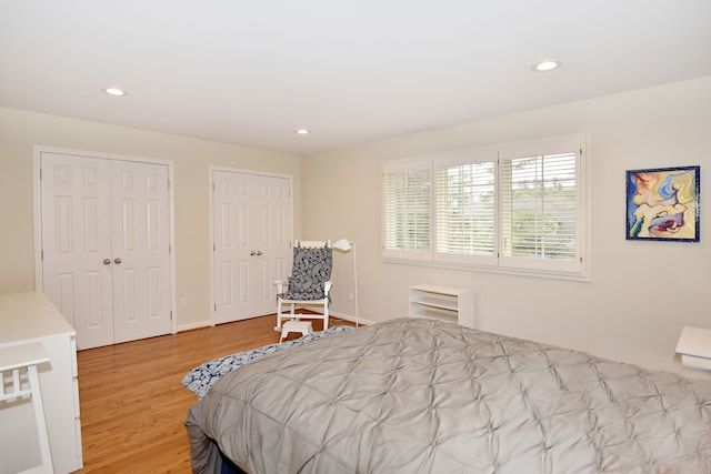 bedroom featuring baseboards, recessed lighting, wood finished floors, and multiple closets