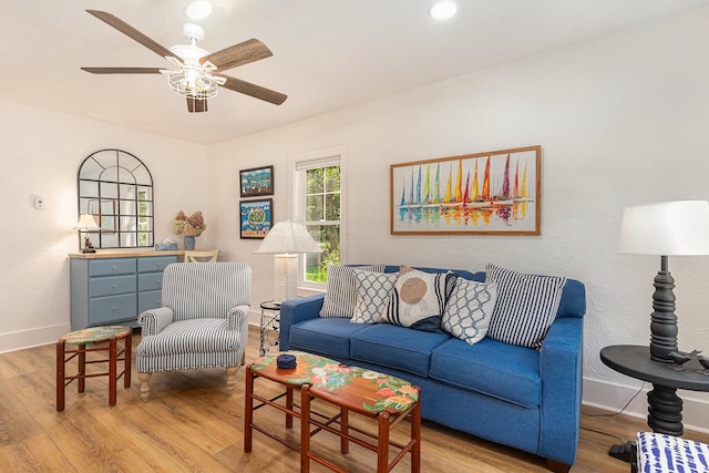 living room featuring baseboards, ceiling fan, and light wood finished floors