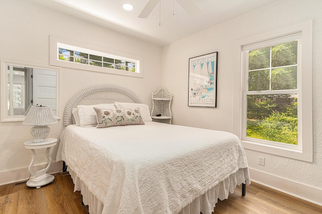 bedroom featuring multiple windows, ceiling fan, baseboards, and wood finished floors