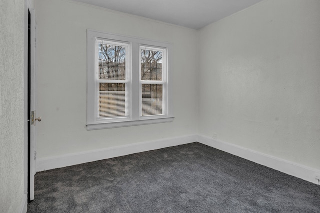 empty room with dark colored carpet and baseboards