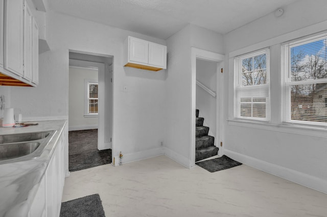 kitchen with white cabinets, a sink, and baseboards