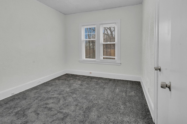 unfurnished room with baseboards and dark colored carpet